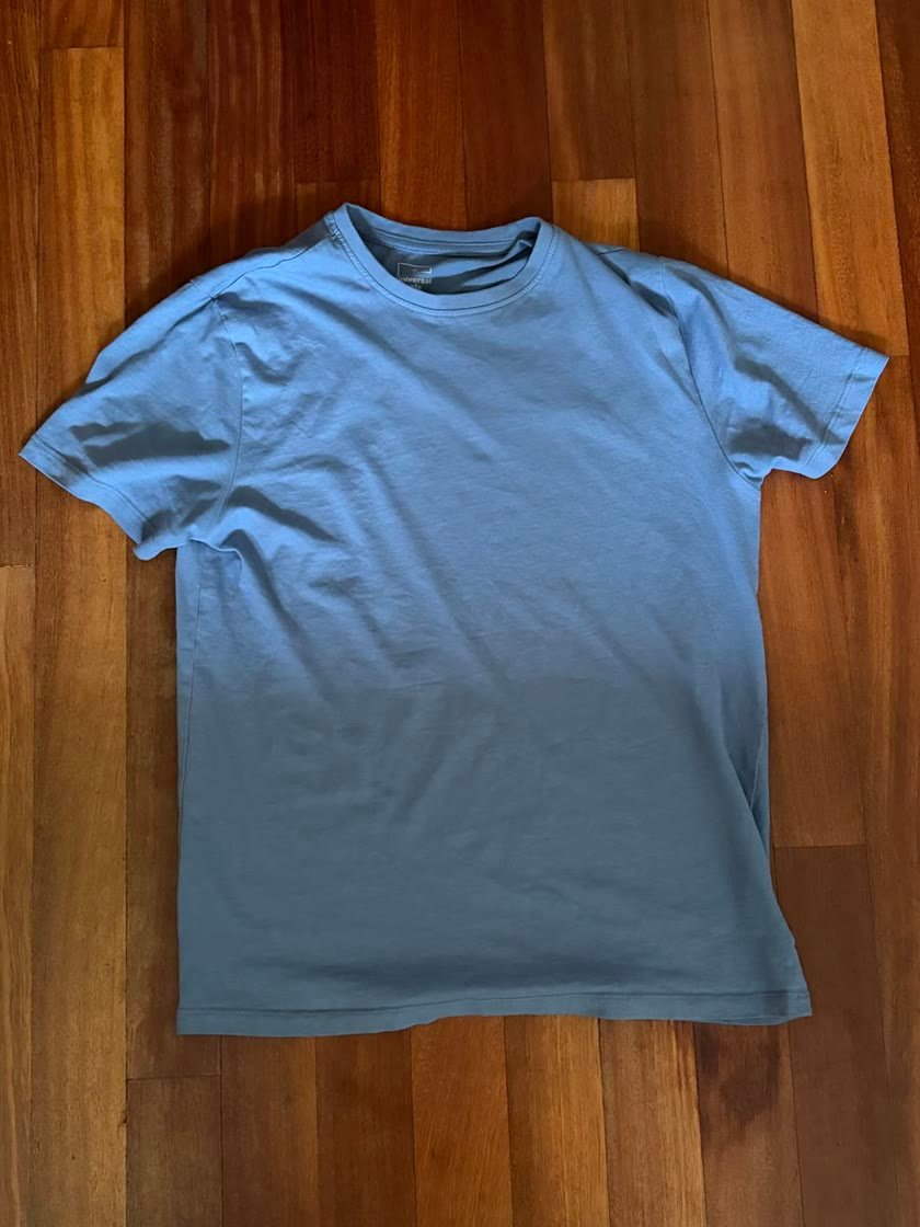 Tu foto: camiseta azul arrugada sobre un suelo de madera