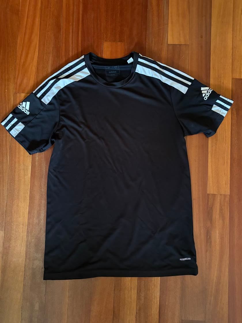 Tu foto: camiseta negra de adidas sobre un suelo de madera